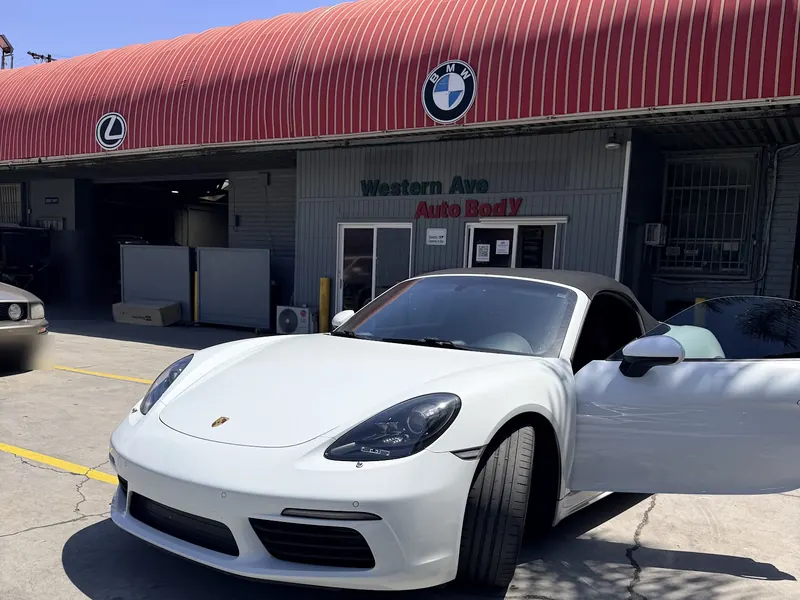 White Porsche parked at the Western Ave Auto Body entrance under the red awning